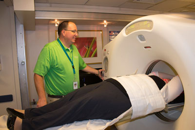 PET/CT technologist raising a patient inside the PET/CT scanner
