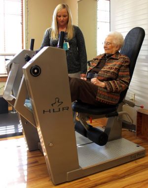 Resident working with therapist on exercise equipment in the therapy gym