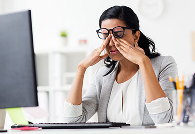 woman sitting in office at computer, itching her eyes